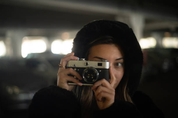 Young and beautiful woman taking photos with a retro camera.