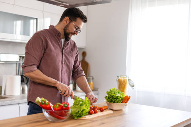 istock Handsome young man man stand at modern kitchen chop vegetables prepare fresh vegetable salad for dinner or lunch, young male cooking at home make breakfast follow healthy diet, vegetarian concept 2199938547