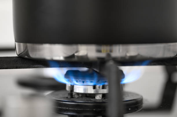 istock Gas stove burner close-up with blue flame, pot on it 2199939288