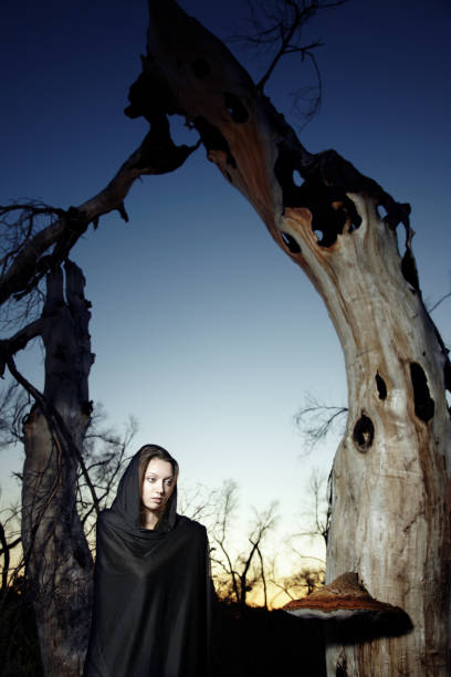 istock Religious lady in cape near the old bizarre trees 2199939659