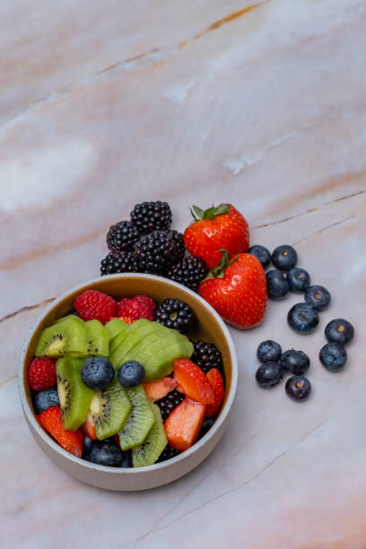 istock Fruit salad bowl with fresh ingredients, table top view, vertical 2199942757