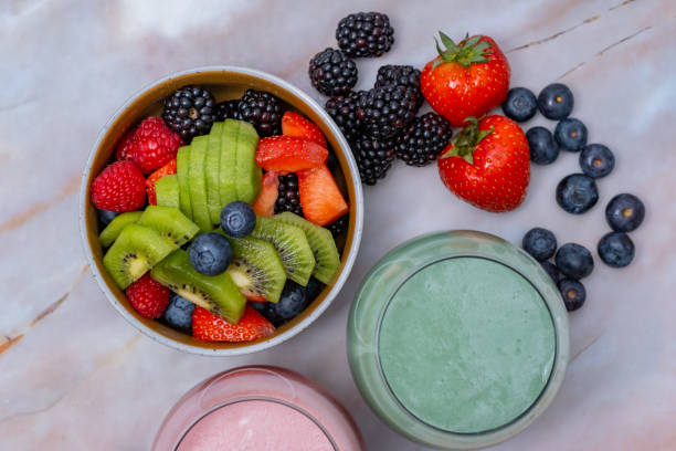 Green fruits cold press juice, berry smoothie and fruit salad table top view