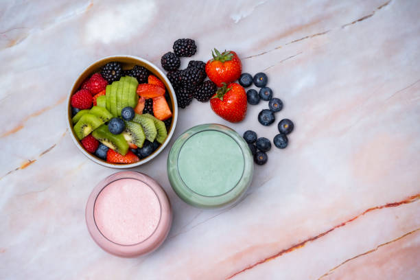 Green fruits cold press juice, berry smoothie and fruit salad table top view