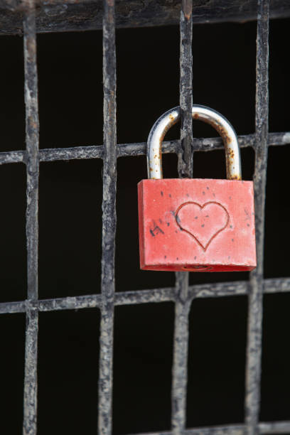 istock A red lock with engraved heart secured onto a wire fence. 2199943073