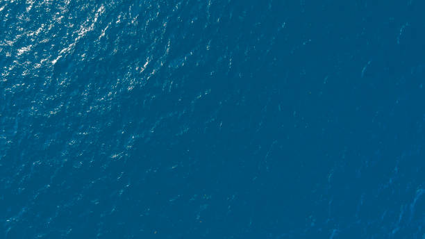 istock Flat lay top view of Ocean blue and calm with sun rays reflection on smooth waves as textured blue background for banner template or web page design. Water calm with smooth waves. 2199945670
