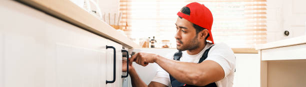 istock Professional handyman in uniform installing a kitchen cabinet handle. Home repair, renovation, and maintenance services concept. Skilled worker using a screwdriver for cabinet fitting. 2199945938