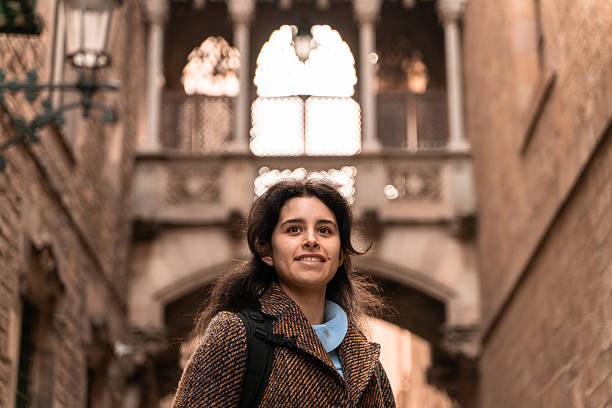 Young woman looking up while walking in the charming streets of the gothic quarter in barcelona, spain