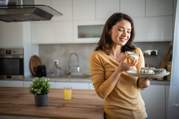 istock Happy woman relishing a donut while relaxing at home 2199961676