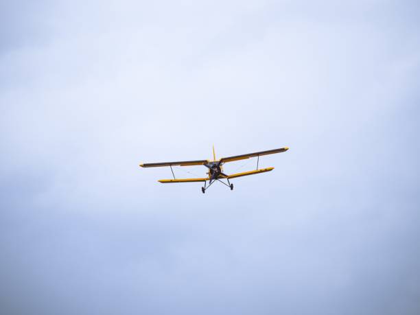 istock Yellow vintage biplane flying against cloudy sky 2199972059
