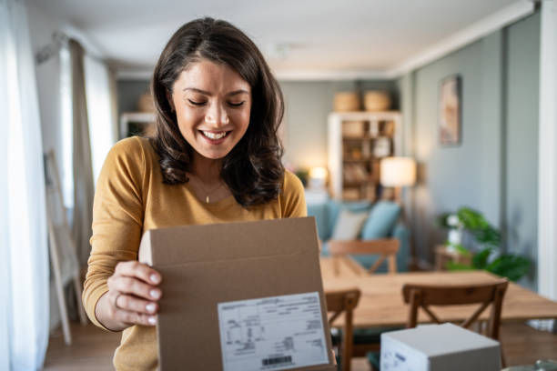 istock Excited young woman opening a package at home 2199972914