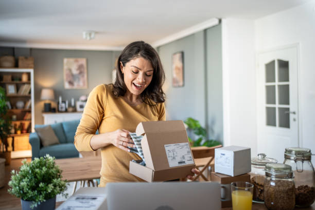 istock Excited young woman opening a package at home 2199972923