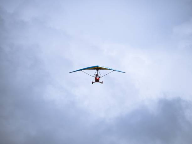 Ultralight trike aircraft flying against cloudy sky
