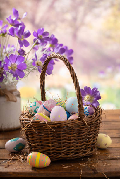 istock Easter eggs in a basket and purple daisies with vibrant spring background 2199974431