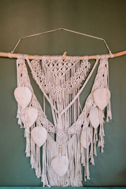 istock Handcrafted macrame wall hanging with delicate leaf embellishments on green wall 2199990597