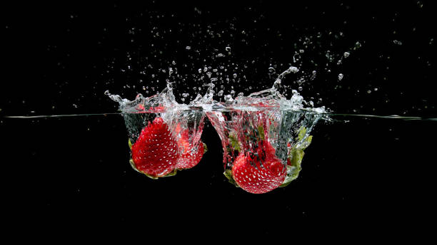 istock Strawberries plunging into water on a black background 2199994216