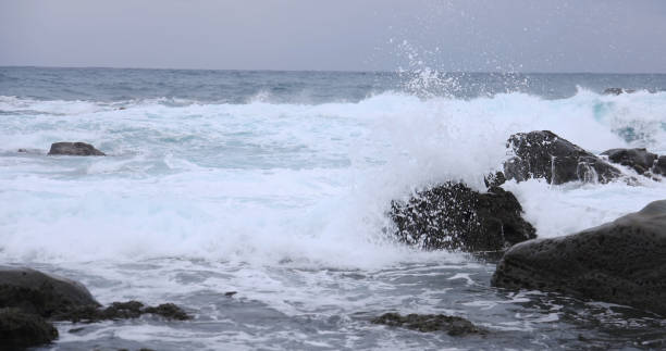Very strong winds and waves crashing against the rocky shore