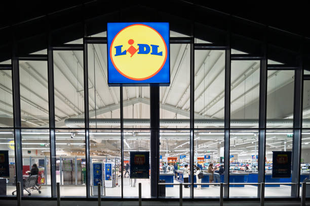 LIDL supermarket bright and inviting at night, highlighting the glass facade and busy shopping environment during evening hours.