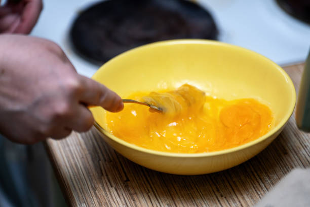 istock Fresh chicken eggs being whisked with a fork in a vibrant yellow ceramic plate, perfect for preparing a delicious omelette 2200004518