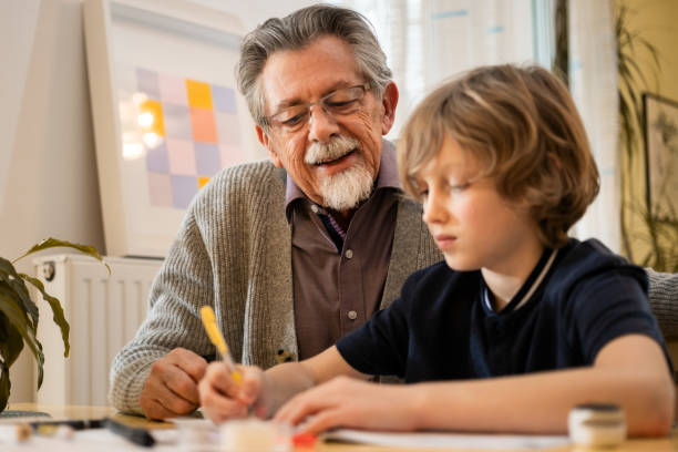 istock Grandfather Helping Grandson with Homework at Home 2200010595
