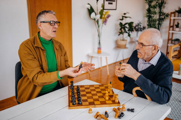 istock Old people care at home playing chess game 2200011948