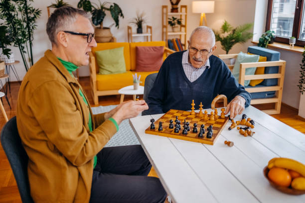 istock Old people care at home playing chess game 2200011970