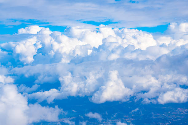 Soft, fluffy clouds drift lazily across a brilliant blue sky, creating a peaceful atmosphere above a tranquil landscape below.