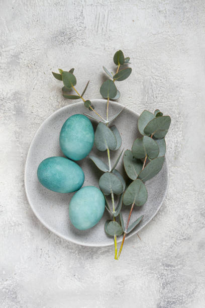 istock Easter colored eggs, in turquoise tones, on a gray plate, with a branch of eucalyptus, Easter card, top view, no people 2200012718