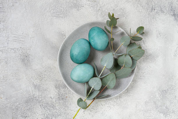 istock Easter colored eggs, in turquoise tones, on a gray plate, with a branch of eucalyptus, Easter card, top view, no people 2200012967