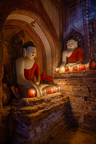 Two buddha statues surrounded by candles in a temple in bagan, myanmar