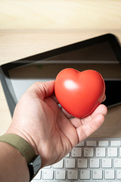 istock Office worker holding red heart at workplace a tablet 2200015389