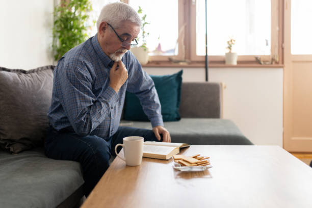 istock Senior man reading a book at home 2200019120