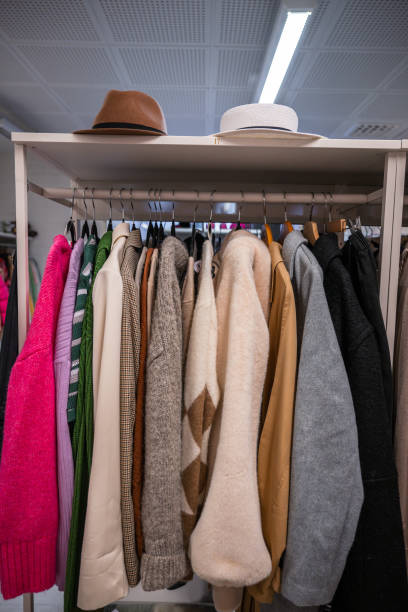 istock Clothing rack filled with sweaters, jackets, and hats in a thrift store. 2200019734