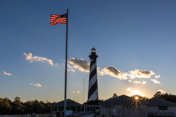 Photo of the Cape Hatteras Lighthouse at dusk with the US Flag in the Foreground