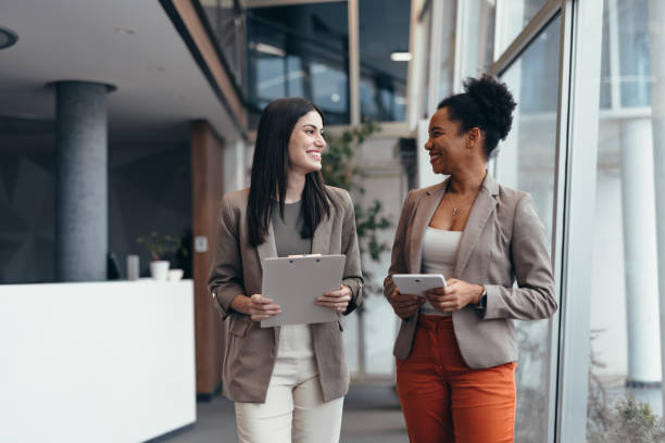 istock Two businesswomen walking and talking in a modern office building 2200020694