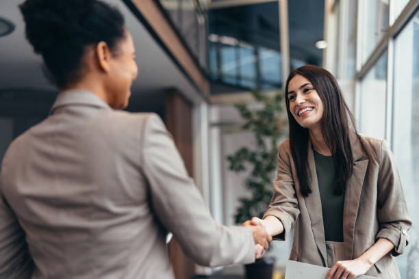 istock Two businesswomen shaking hands in modern office building 2200020765