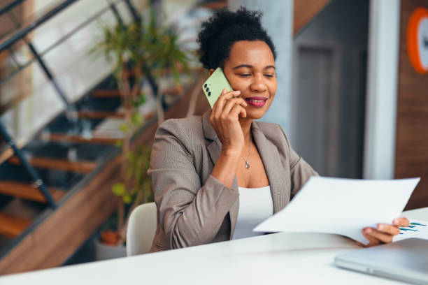 istock Businesswoman talking on phone and reading document at office desk 2200020813