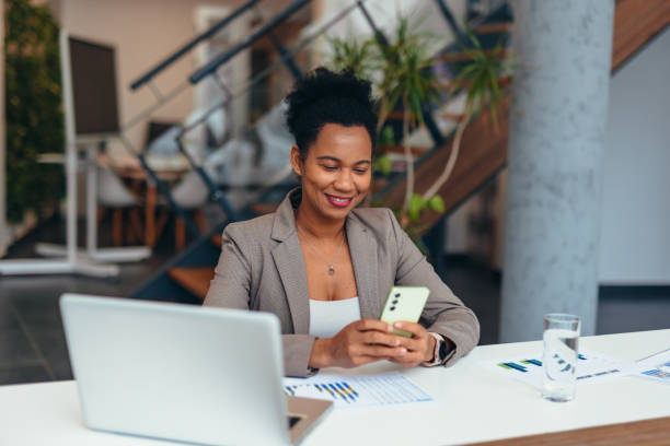 istock Smiling businesswoman using smartphone in modern office 2200020829