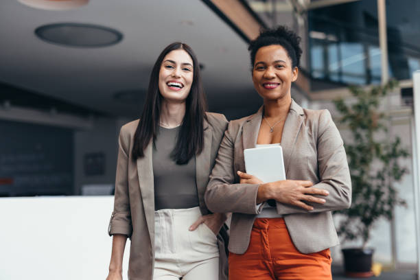 istock Two smiling businesswomen standing in modern office building 2200020848