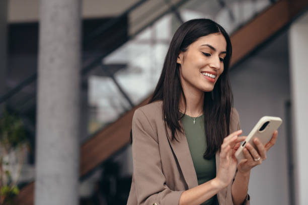istock Smiling businesswoman using mobile phone in modern office 2200020886
