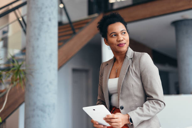 istock Businesswoman holding tablet looking away planning future projects in modern office building 2200021000