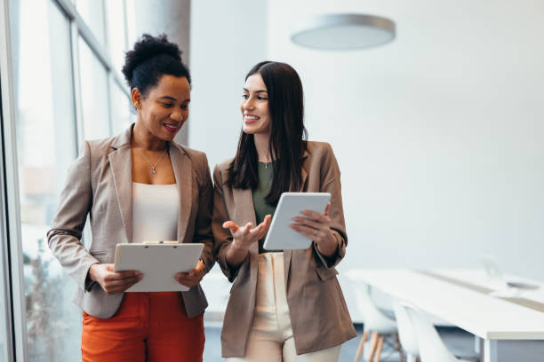 istock Two businesswomen discussing work in modern office using digital tablet and clipboard 2200021065