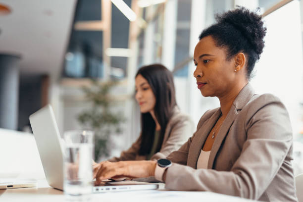 istock Focused businesswomen working on laptops in modern office 2200021136