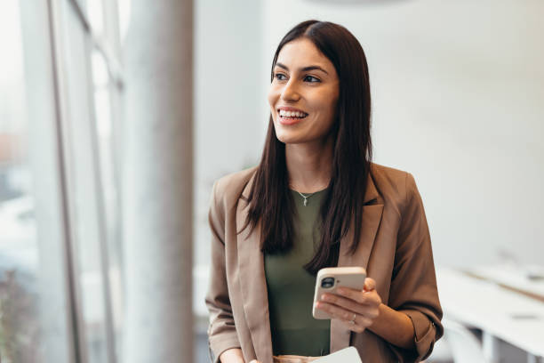 istock Young businesswoman smiling and using smartphone in office 2200021836