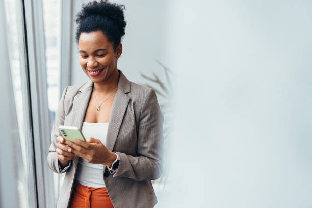 istock Smiling businesswoman using smartphone next to office window 2200021854