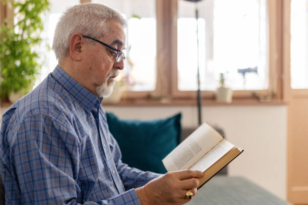 istock Senior man reading a book at home 2200023550