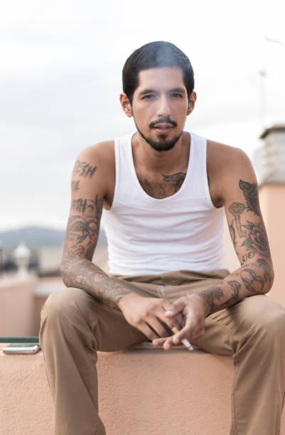 istock Young latino man smoking a cigarette on a rooftop 2200028939
