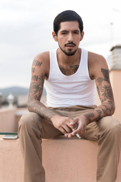 istock Young latino man smoking a cigarette on a rooftop 2200028941