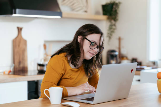 istock Young woman with Down Syndrome using computer at home 2200034465