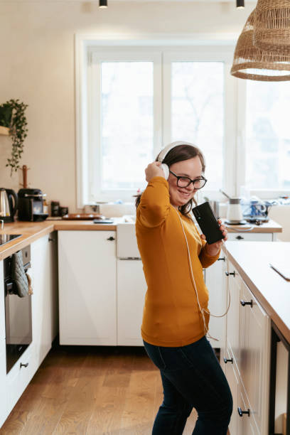 istock Young woman with Down Syndrome dancing and singing in the kitchen 2200035047