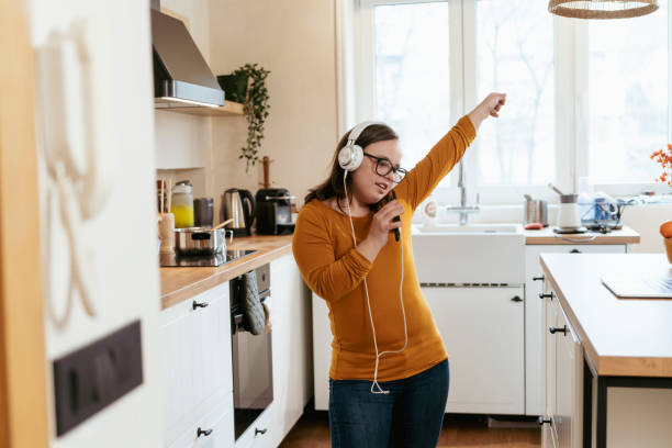 istock Young woman with Down Syndrome dancing and singing in the kitchen 2200035121